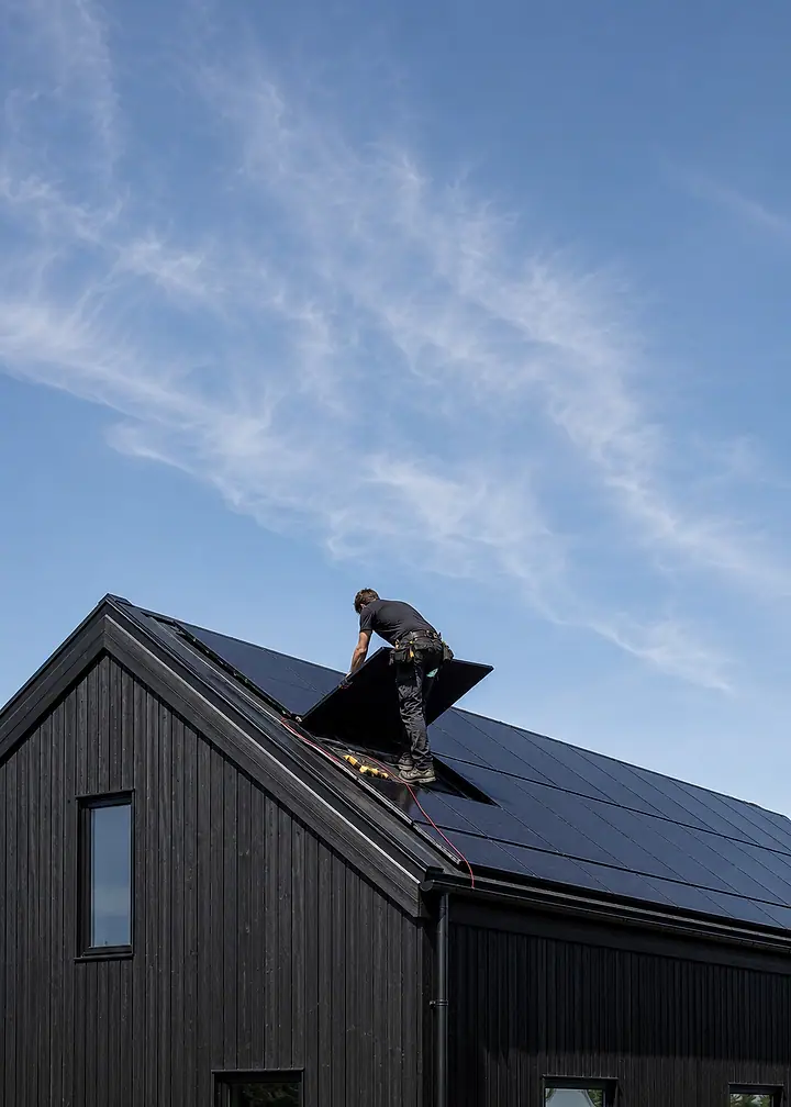 An installer fitting solar modules to the roof of a newly built house.